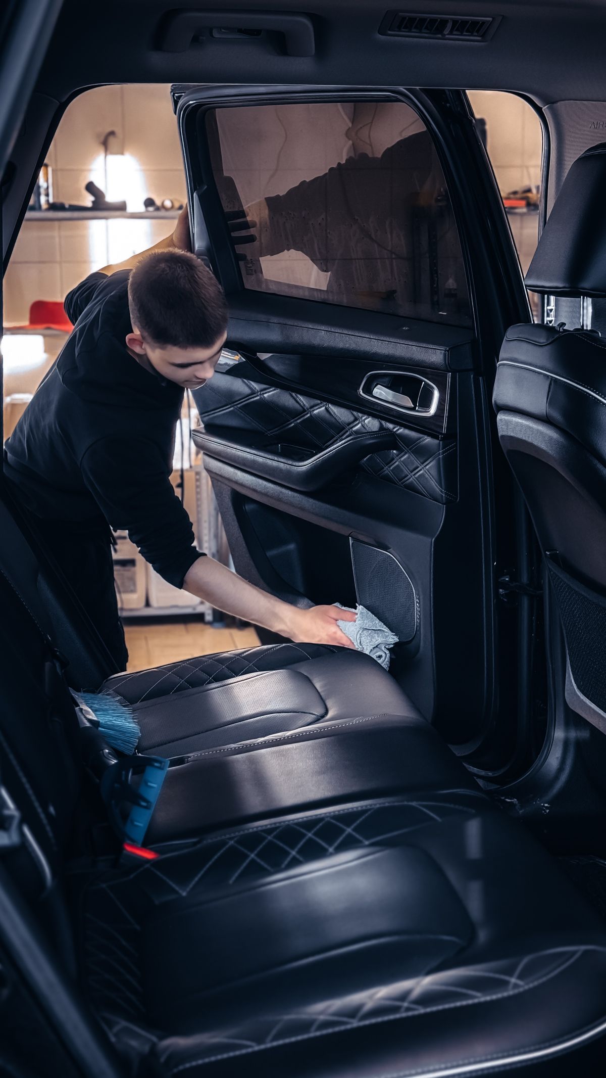 Detailer deep cleaning a car door panel and interior trim