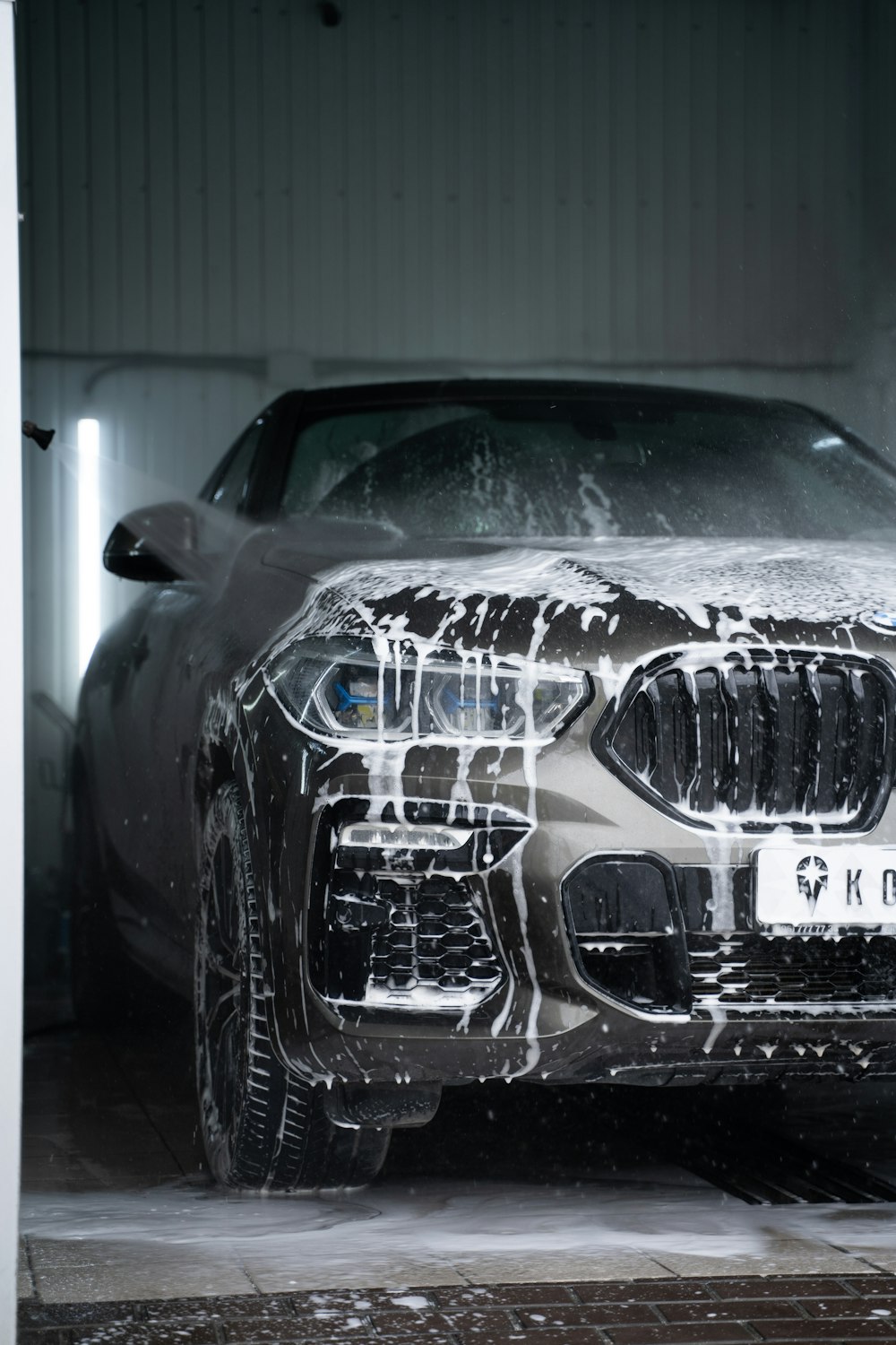 Grey car covered in white soap suds during a professional wash