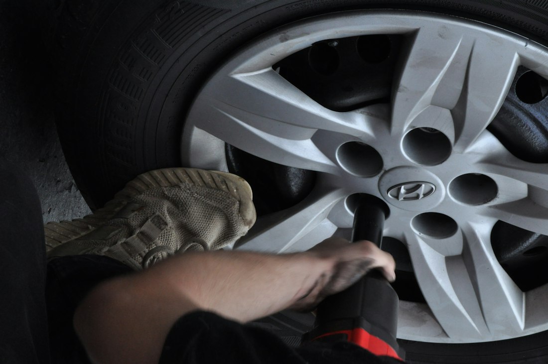 Mechanic using an impact wrench on a car wheel
