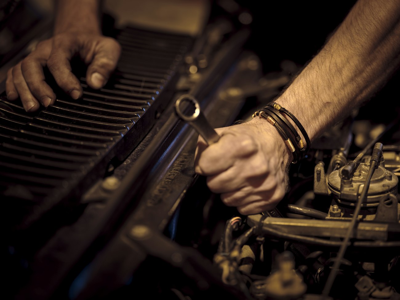 Mechanic hands working on an engine with a wrench