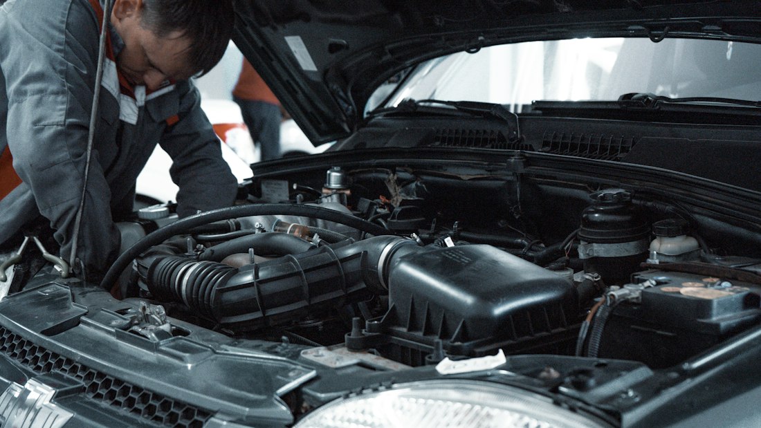 Mechanic in uniform inspecting a car engine bay