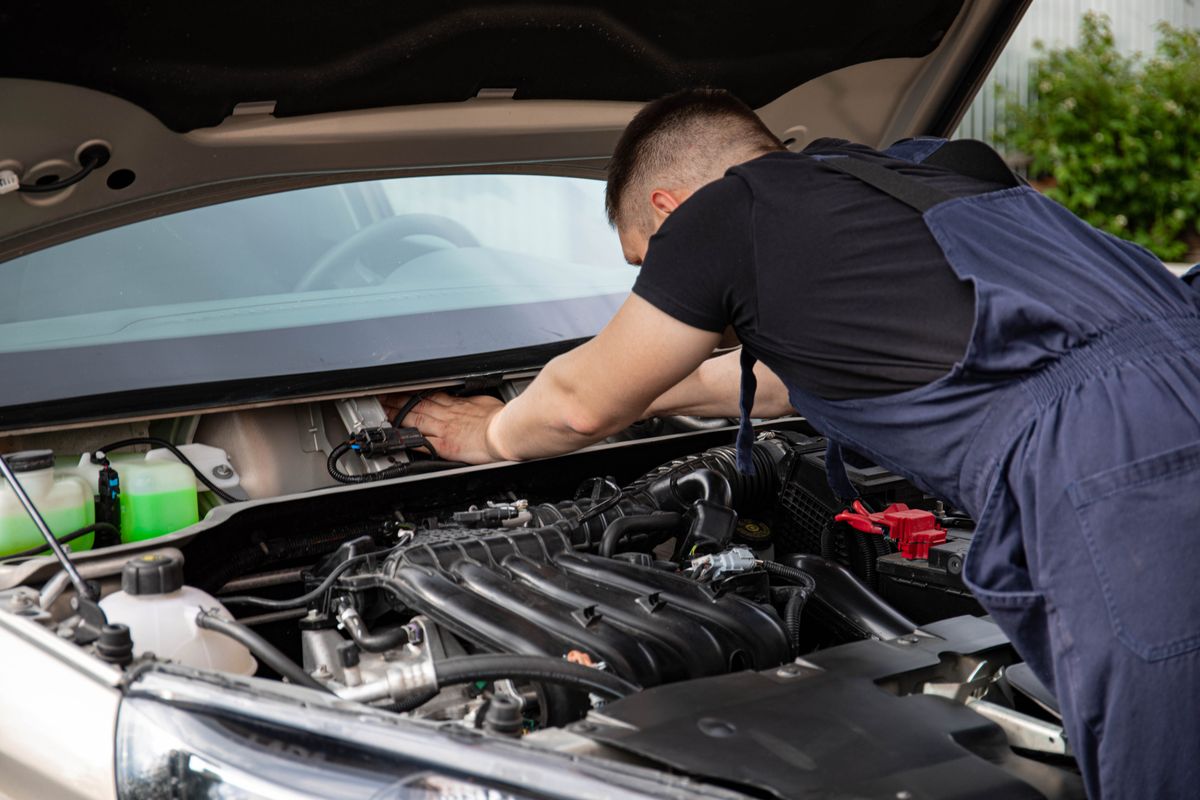 Mechanic leaning under an open bonnet checking the engine