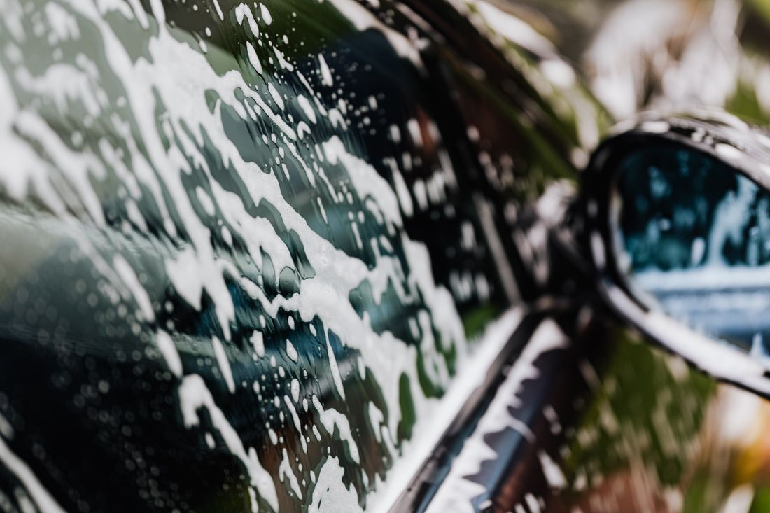 Close view of soapy foam sliding down a car panel