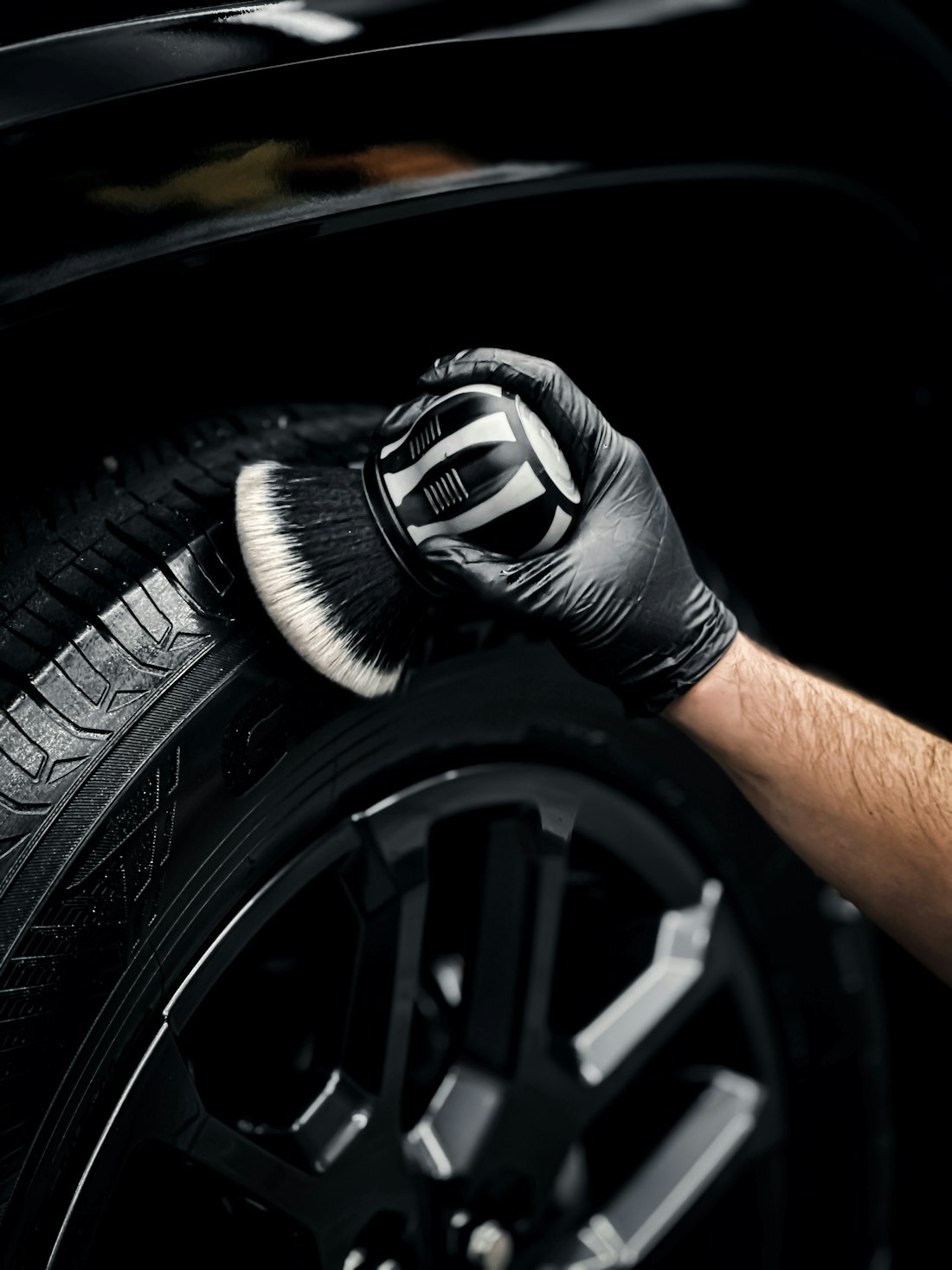 Gloved hand cleaning a tyre sidewall with a brush